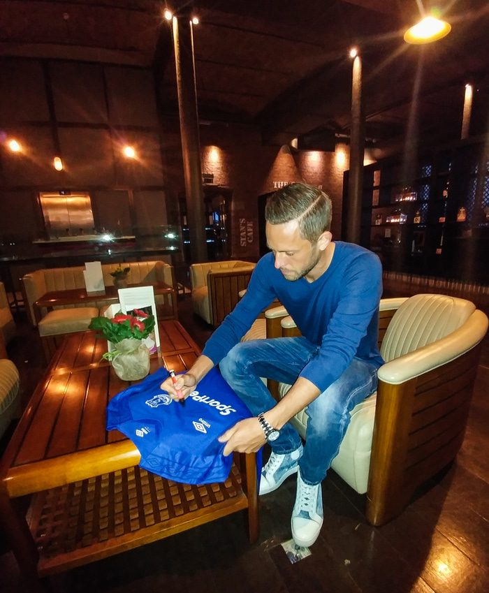 Gylfi áritar treyjuna.