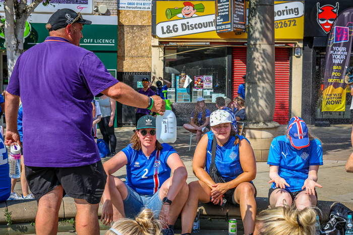 Sjálfboðaliði frá UEFA spreyjar köldu vatni á íslenskt stuðningsfólk.
